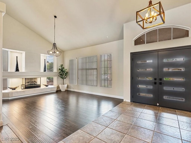 6639 Tranquil Seas Ct, Las Vegas, NV 89139 - entrance foyer featuring a chandelier, high vaulted ceiling, hardwood / wood-style flooring, baseboards, and a glass covered fireplace