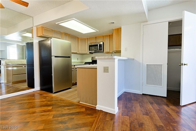 3811 Desert Marina Dr Unit 125, Laughlin, NV 89029 - kitchen with stainless steel appliances, a peninsula, light countertops, hardwood / wood-style flooring, and baseboards