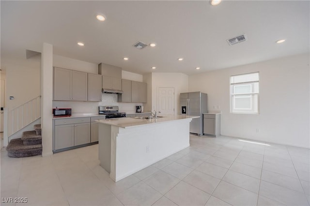 5927 Coja St, Las Vegas, NV 89113 - kitchen featuring appliances with stainless steel finishes, gray cabinetry, light countertops, a sink, and an island with sink