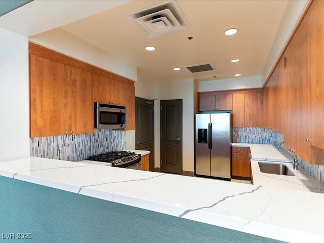 38 E Serene Ave Unit 134, Las Vegas, NV 89123 - kitchen with appliances with stainless steel finishes, a sink, backsplash, brown cabinets, and recessed lighting