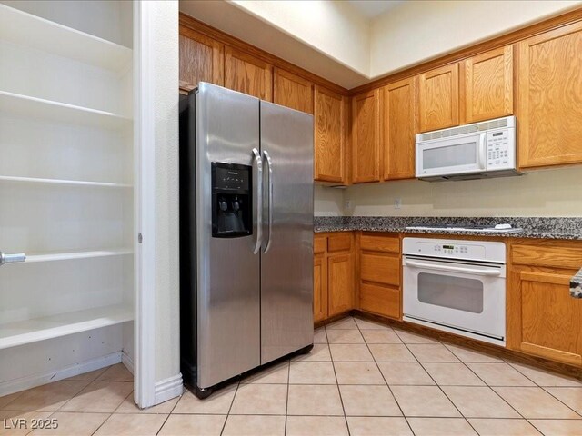 38 E Serene Ave Unit 134, Las Vegas, NV 89123 - kitchen featuring white appliances, light tile patterned floors, brown cabinets, and dark stone countertops