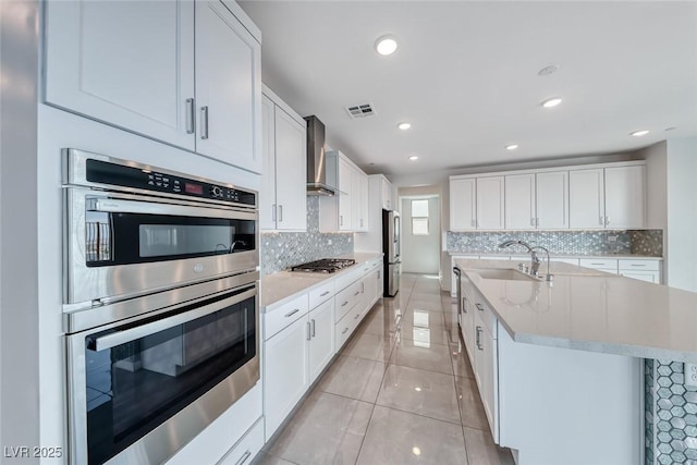 1038 Delbrook Ave, Henderson, NV 89012 - kitchen featuring wall chimney exhaust hood, appliances with stainless steel finishes, tasteful backsplash, white cabinets, and recessed lighting