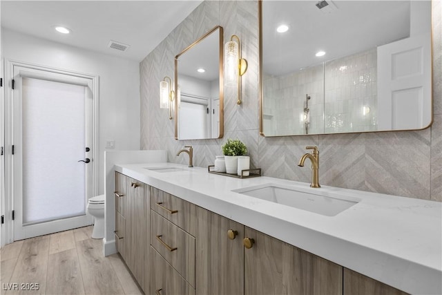 2250 Bowie Cir, Henderson, NV 89014 - full bath with toilet, double vanity, wood finished floors, decorative backsplash, and recessed lighting