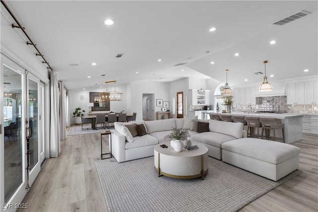 2250 Bowie Cir, Henderson, NV 89014 - living room with vaulted ceiling, light wood-style floors, recessed lighting, plenty of natural light, and a chandelier