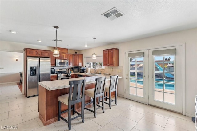 1912 Parkchester Dr, Las Vegas, NV 89108 - kitchen featuring stainless steel appliances, tasteful backsplash, a kitchen bar, hanging light fixtures, and recessed lighting