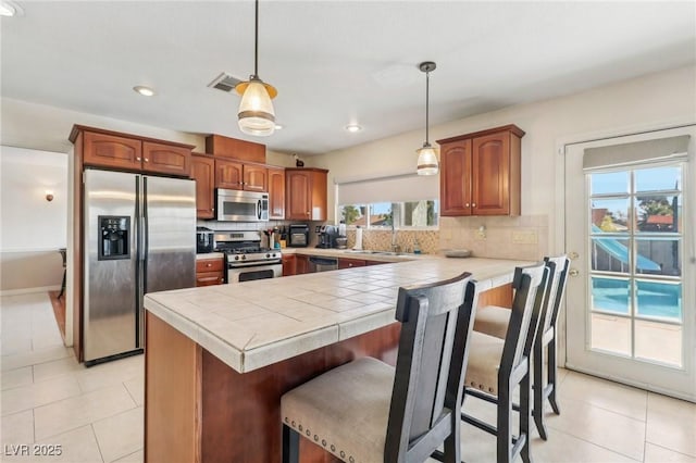 1912 Parkchester Dr, Las Vegas, NV 89108 - kitchen featuring appliances with stainless steel finishes, a peninsula, tasteful backsplash, light tile patterned floors, and recessed lighting