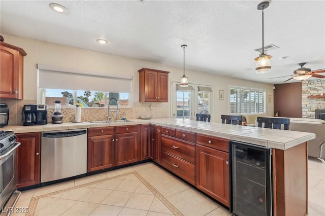 1912 Parkchester Dr, Las Vegas, NV 89108 - kitchen with stainless steel appliances, beverage cooler, a sink, a peninsula, and backsplash