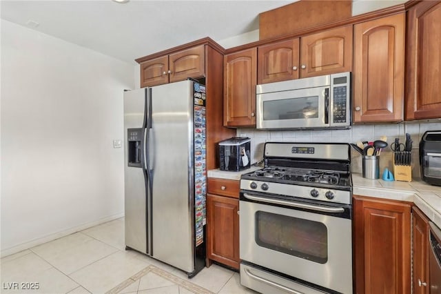 1912 Parkchester Dr, Las Vegas, NV 89108 - kitchen featuring appliances with stainless steel finishes, tasteful backsplash, light tile patterned floors, baseboards, and brown cabinets