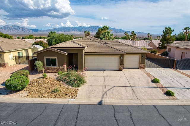 854 Santa Maria Way, Mesquite, NV 89027 - view of front of house with a garage, stucco siding, a gate, concrete driveway, and a mountain view