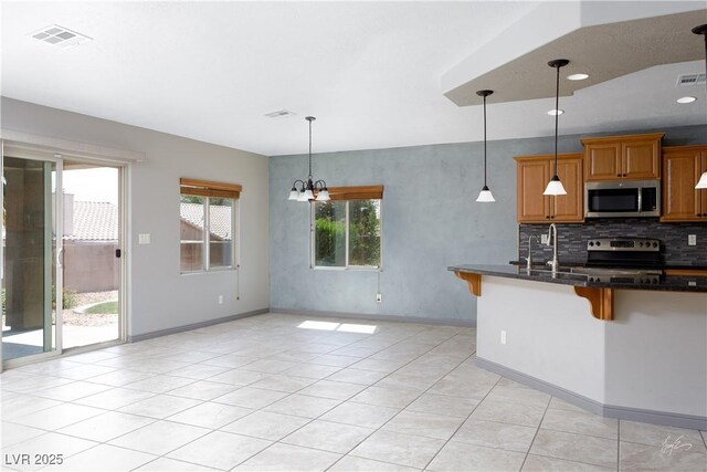 854 Santa Maria Way, Mesquite, NV 89027 - kitchen with electric stove, stainless steel microwave, a kitchen breakfast bar, light tile patterned floors, and baseboards