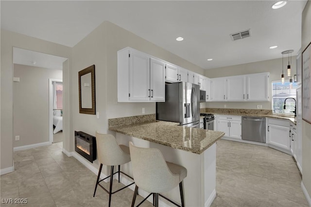 2558 Wiltshire Ave, Henderson, NV 89052 - kitchen featuring appliances with stainless steel finishes, light stone counters, a peninsula, white cabinets, and recessed lighting