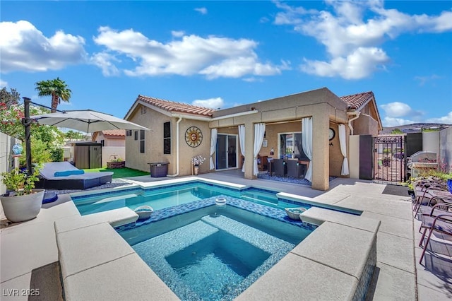 2558 Wiltshire Ave, Henderson, NV 89052 - rear view of house with a gate, stucco siding, a tiled roof, a pool with connected hot tub, and a patio