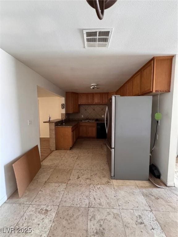 2604 Webster St, North Las Vegas, NV 89030 - kitchen featuring freestanding refrigerator, brown cabinets, tasteful backsplash, dark countertops, and a sink