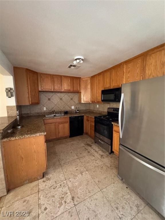 2604 Webster St, North Las Vegas, NV 89030 - kitchen featuring black appliances, decorative backsplash, brown cabinets, a sink, and dark stone countertops