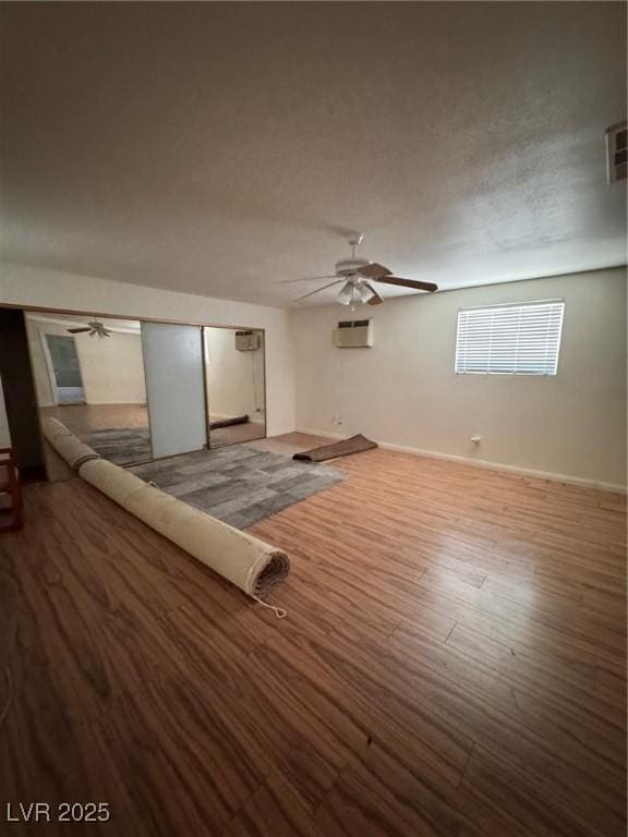 2604 Webster St, North Las Vegas, NV 89030 - unfurnished living room with a ceiling fan, a wall mounted AC, wood finished floors, and baseboards