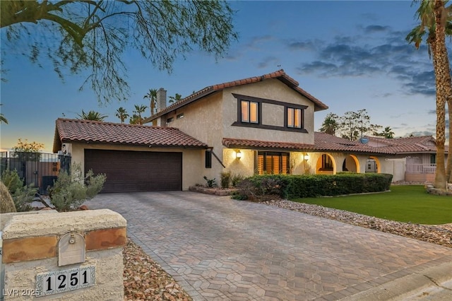 1251 Los Meadows Dr, Las Vegas, NV 89110 - mediterranean / spanish home featuring a garage, decorative driveway, stucco siding, a chimney, and a tile roof