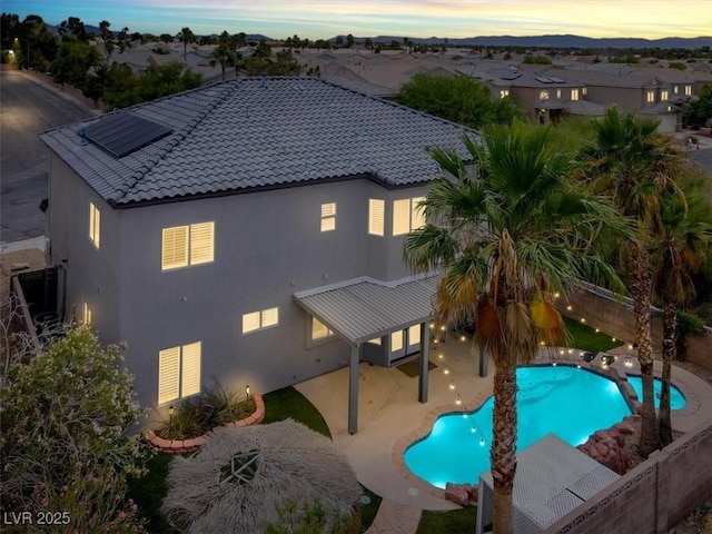 3204 Rutledge Dr, Las Vegas, NV 89120 - rear view of house featuring a tile roof, stucco siding, a patio area, solar panels, and a fenced backyard
