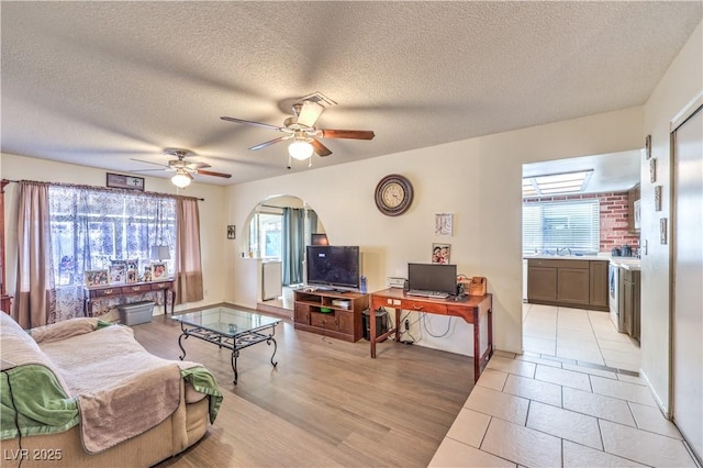 5809 Robin Ln, Las Vegas, NV 89108 - living area featuring arched walkways, ceiling fan, a textured ceiling, baseboards, and light tile patterned floors