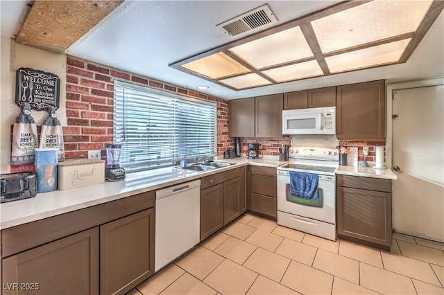5809 Robin Ln, Las Vegas, NV 89108 - kitchen featuring white appliances, a sink, light countertops, brick wall, and light tile patterned floors