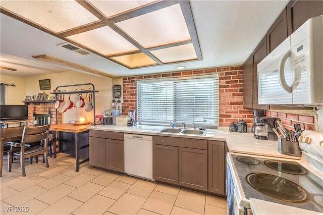 5809 Robin Ln, Las Vegas, NV 89108 - kitchen featuring white appliances, a sink, plenty of natural light, light countertops, and brick wall