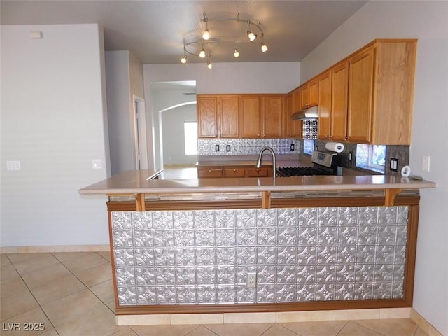 2905 Shimmering Bay St, Laughlin, NV 89029 - kitchen with under cabinet range hood, stainless steel range, arched walkways, and light tile patterned flooring