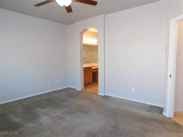 2905 Shimmering Bay St, Laughlin, NV 89029 - unfurnished bedroom with arched walkways, light colored carpet, baseboards, a ceiling fan, and connected bathroom