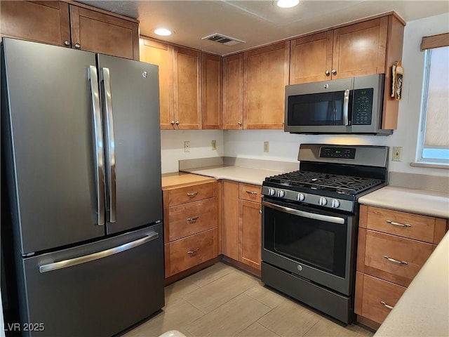 2106 Pebble Creek Ln, Laughlin, NV 89029 - kitchen with appliances with stainless steel finishes, light countertops, recessed lighting, and brown cabinetry