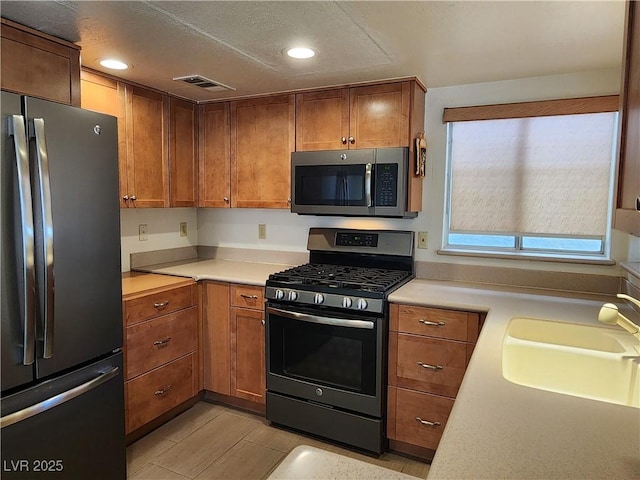 2106 Pebble Creek Ln, Laughlin, NV 89029 - kitchen with appliances with stainless steel finishes, a sink, light countertops, recessed lighting, and brown cabinetry