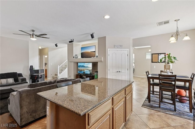 10329 Walworth Ave, Las Vegas, NV 89166 - kitchen with a kitchen island, a ceiling fan, hanging light fixtures, light stone countertops, and a chandelier
