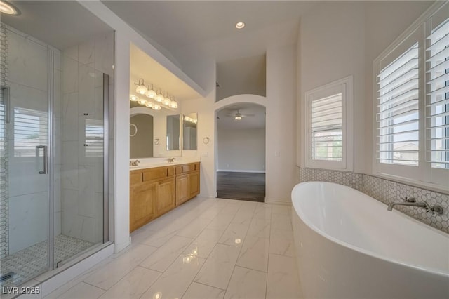 9792 Crescent Lodge Ct, Las Vegas, NV 89178 - bathroom with double vanity, a soaking tub, a shower stall, marble finish floors, and ceiling fan