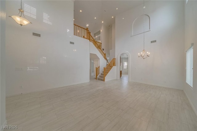 9792 Crescent Lodge Ct, Las Vegas, NV 89178 - unfurnished living room with a chandelier, stairs, a high ceiling, baseboards, and arched walkways