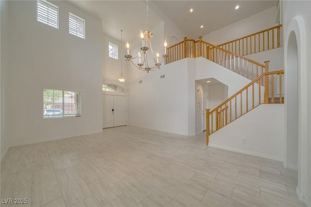 9792 Crescent Lodge Ct, Las Vegas, NV 89178 - unfurnished living room featuring a high ceiling, stairs, plenty of natural light, a chandelier, and arched walkways