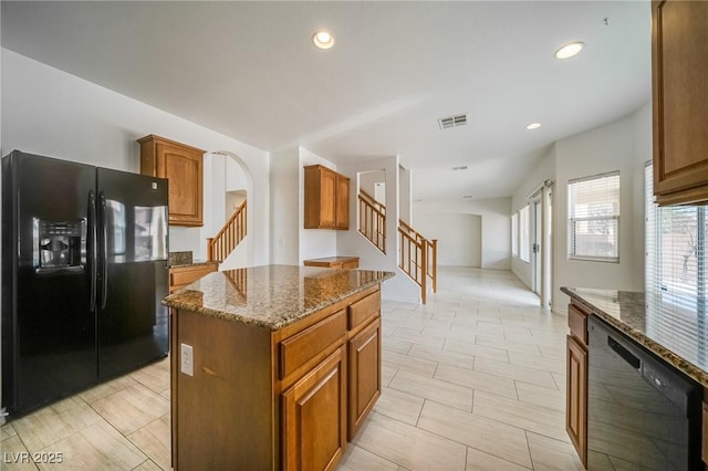 9792 Crescent Lodge Ct, Las Vegas, NV 89178 - kitchen with black appliances, dark stone countertops, a center island, brown cabinets, and recessed lighting