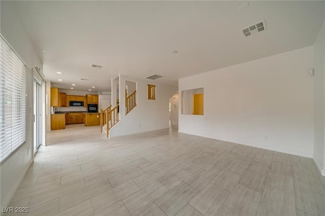 9792 Crescent Lodge Ct, Las Vegas, NV 89178 - unfurnished living room featuring stairway, baseboards, recessed lighting, and a sink