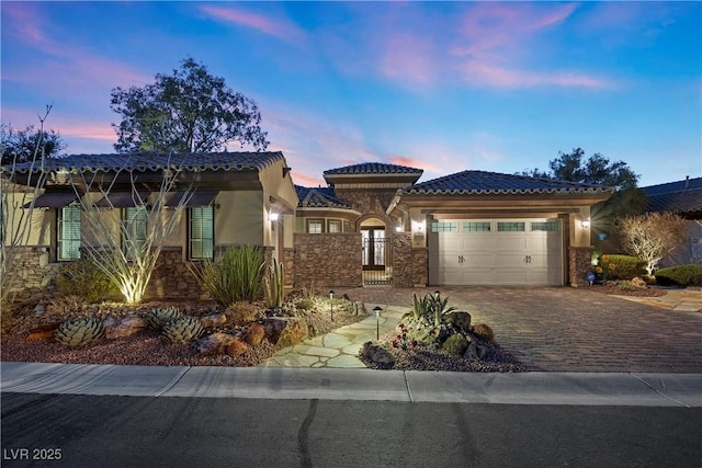 2749 Liberation Dr, Henderson, NV 89044 - mediterranean / spanish house featuring an attached garage, stone siding, driveway, stucco siding, and a tiled roof