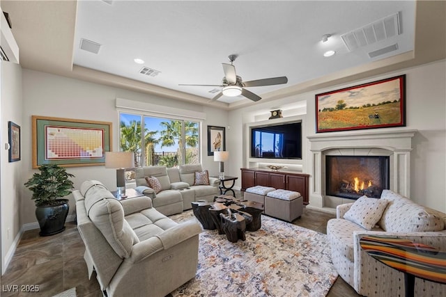 2749 Liberation Dr, Henderson, NV 89044 - living area with ceiling fan, a warm lit fireplace, baseboards, a tray ceiling, and recessed lighting
