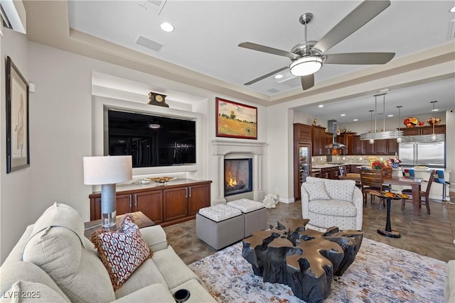 2749 Liberation Dr, Henderson, NV 89044 - living area featuring a raised ceiling, ceiling fan, recessed lighting, and a warm lit fireplace