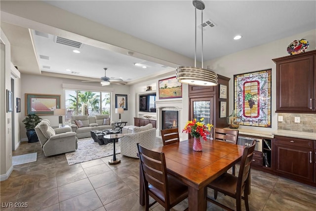 2749 Liberation Dr, Henderson, NV 89044 - dining space with a glass covered fireplace, ceiling fan, baseboards, and recessed lighting