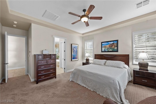 2749 Liberation Dr, Henderson, NV 89044 - bedroom featuring light carpet, baseboards, ceiling fan, ensuite bathroom, and a raised ceiling