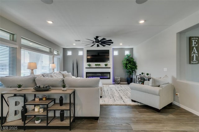 7077 Sunland Hills Ave, Las Vegas, NV 89113 - living room featuring plenty of natural light, a glass covered fireplace, ceiling fan, wood finished floors, and recessed lighting
