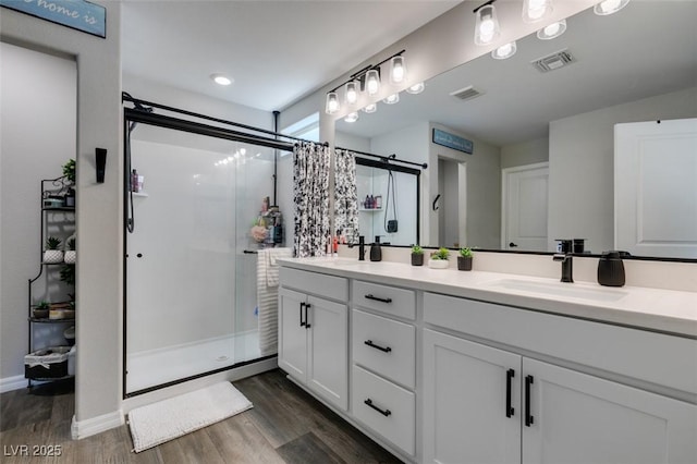 7077 Sunland Hills Ave, Las Vegas, NV 89113 - bathroom featuring a shower stall, wood finished floors, double vanity, and baseboards