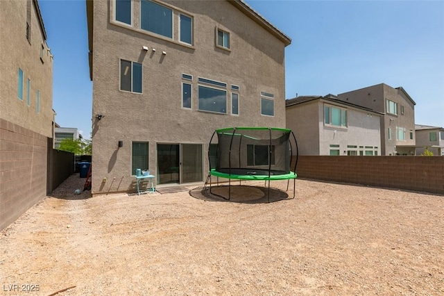 7077 Sunland Hills Ave, Las Vegas, NV 89113 - rear view of property featuring a trampoline, stucco siding, and a fenced backyard