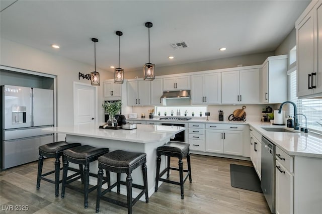 7077 Sunland Hills Ave, Las Vegas, NV 89113 - kitchen with refrigerator with ice dispenser, a sink, dishwasher, under cabinet range hood, and a breakfast bar