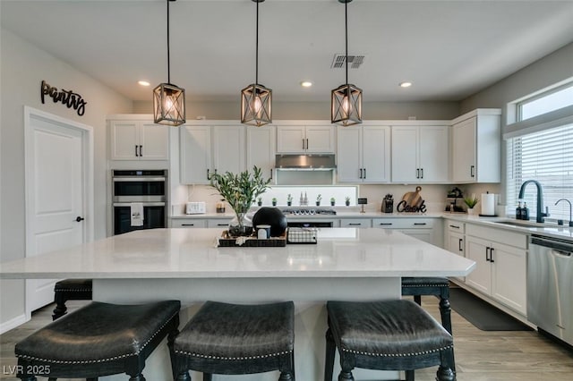7077 Sunland Hills Ave, Las Vegas, NV 89113 - kitchen featuring a sink, stainless steel appliances, white cabinetry, light wood finished floors, and recessed lighting