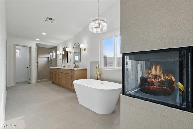 8032 Deep Stone Ave, Las Vegas, NV 89149 - full bath featuring a freestanding tub, double vanity, a chandelier, tile patterned floors, and a glass covered fireplace
