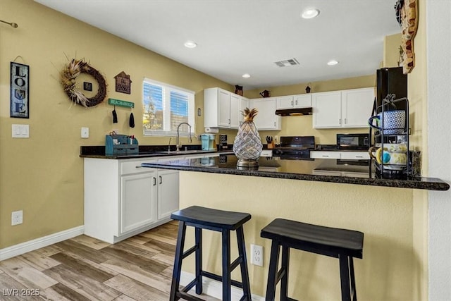 9236 Keystone Ridge Ave, Las Vegas, NV 89148 - kitchen with stove, under cabinet range hood, a peninsula, white cabinetry, and recessed lighting