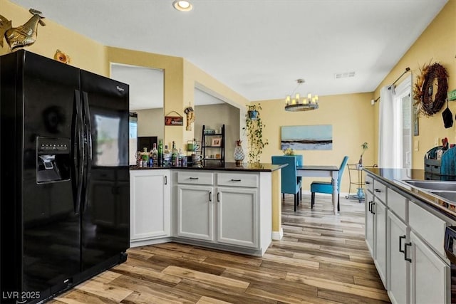 9236 Keystone Ridge Ave, Las Vegas, NV 89148 - kitchen with black fridge, dark countertops, wood finished floors, a chandelier, and recessed lighting