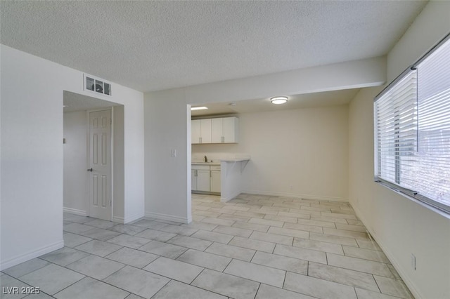 212 Orland St Unit 28, Las Vegas, NV 89107 - unfurnished living room featuring a textured ceiling, a sink, and light tile patterned floors