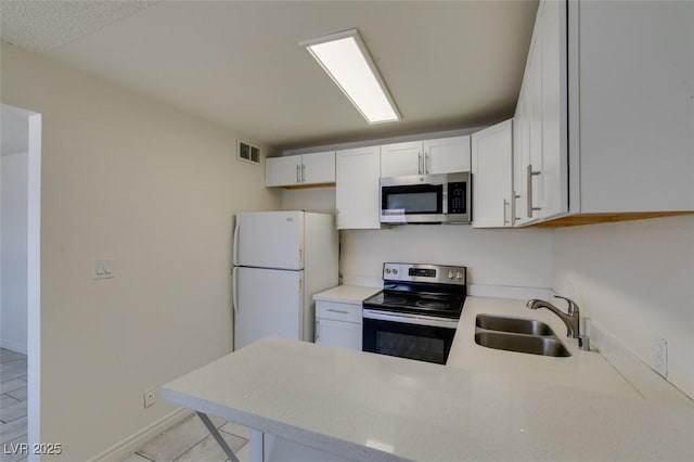 212 Orland St Unit 28, Las Vegas, NV 89107 - kitchen featuring stainless steel microwave, range with electric stovetop, freestanding refrigerator, a sink, and a peninsula