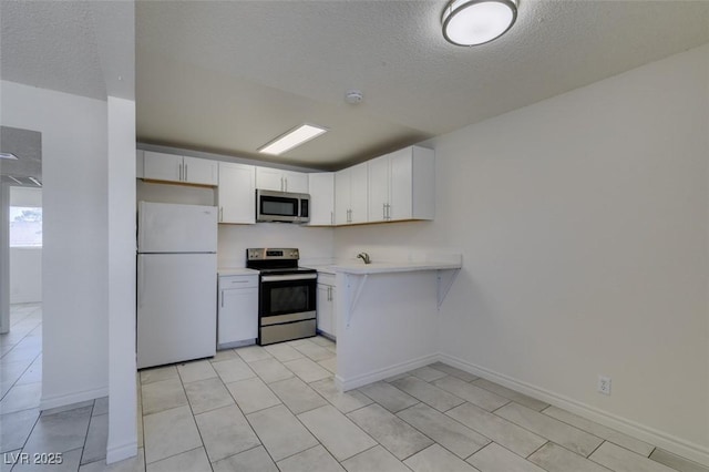 212 Orland St Unit 28, Las Vegas, NV 89107 - kitchen with appliances with stainless steel finishes, a textured ceiling, light countertops, white cabinets, and baseboards
